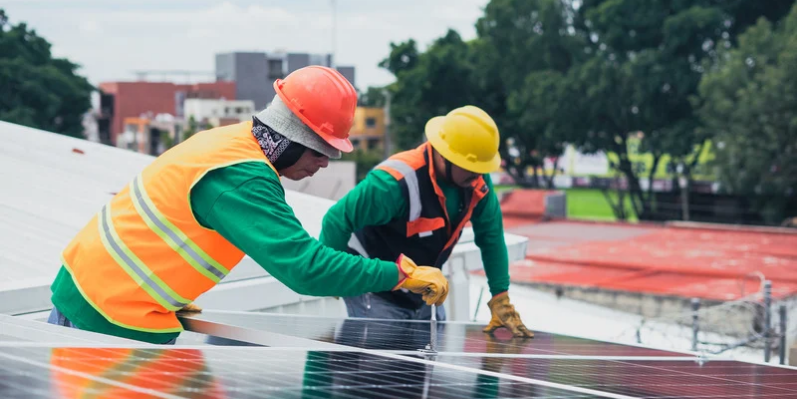 The role of software in ensuring sustainable manufacturing maintenance. Two workers installing solar panels.